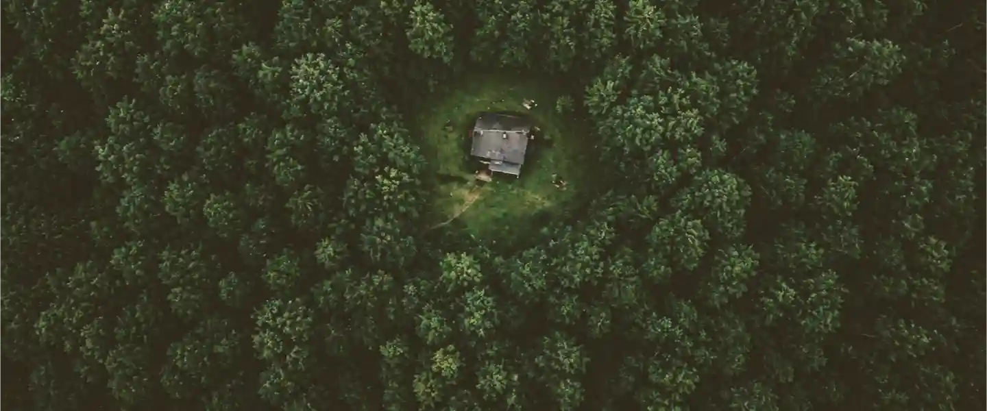 Imagen cenital de una casa sola en el medio de un tupido bosque verde