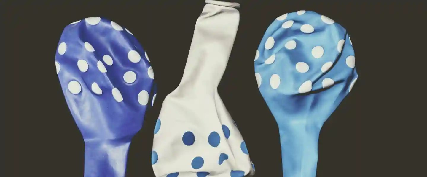 Tres globos desinflados con colores azul, celeste y blanco y pintas celestes y blancas