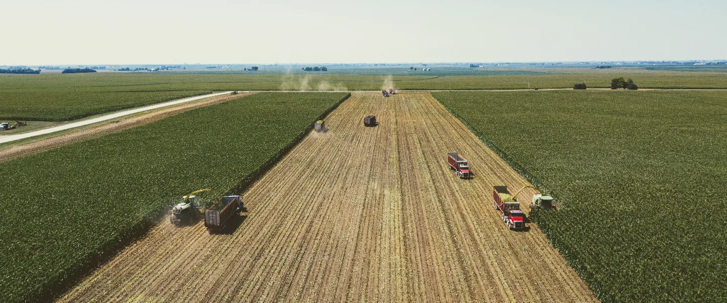 Vista aérea de camiones y cosechadoras trabajando en un campo verde