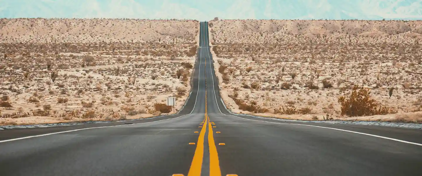 Ruta atravesando en ascenso el desierto americano con las montañas de frente