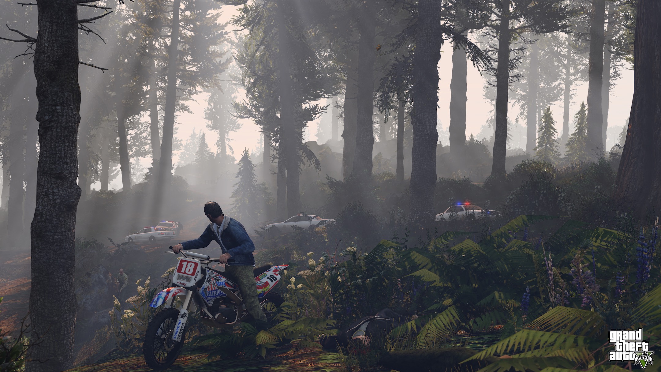 Trevor riding a motorbike through the forest, with police cars in the background.