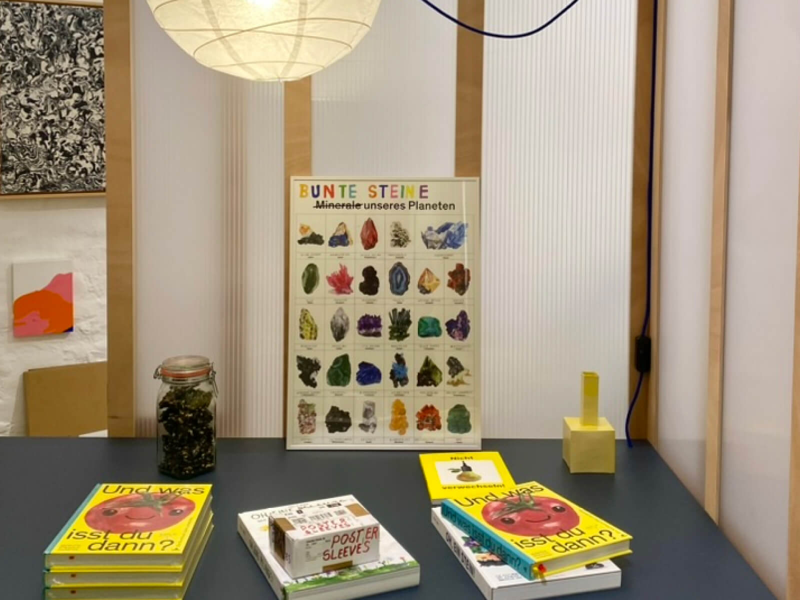 Nahaufnahme des Verkaufsstands von Felix Bork. Zu sehen sind seine Bücher »Und was isst du dann?« und ein Poster mit dem Titel »Bunte Steine«.