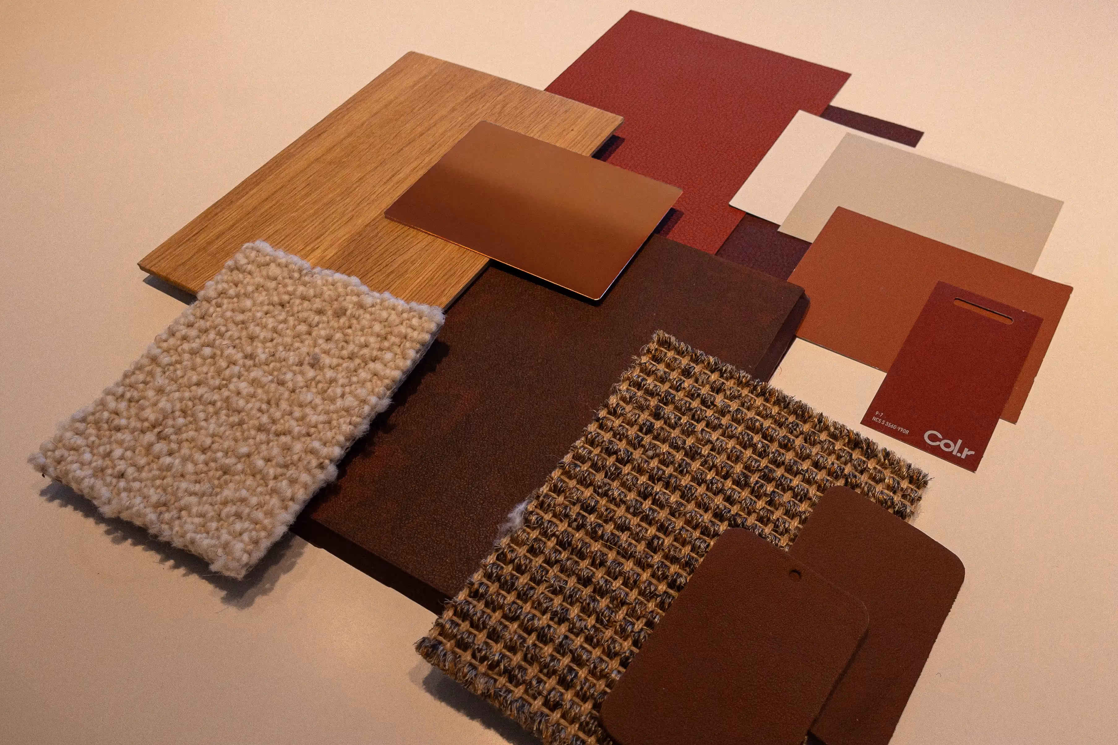 Interior material samples in warm tones, including leather swatches, textured fabrics, wood, and color cards.