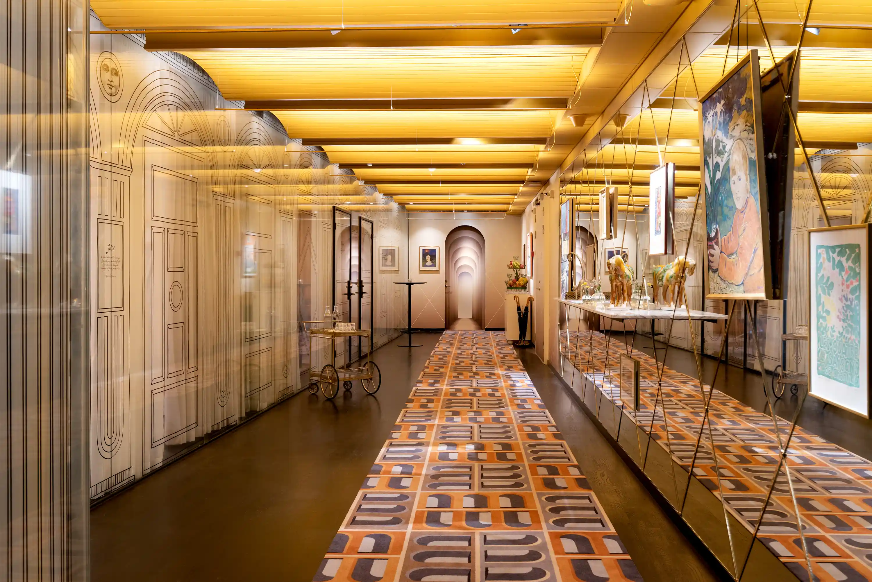 Long hallway with wavy wooded lit ceiling, floor has a long