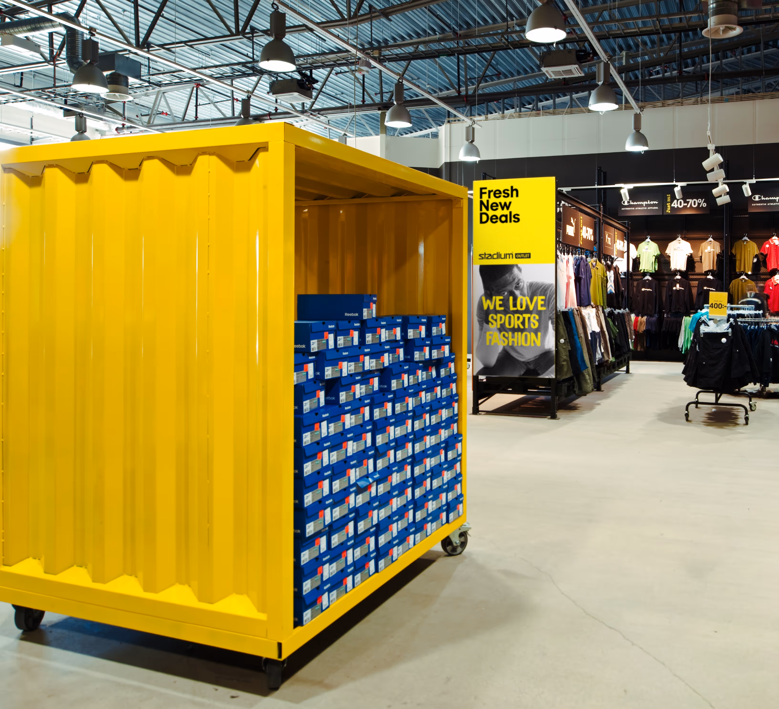 Yellow storage container filled with stacked blue Reebok shoe boxes in a sports fashion retail store.