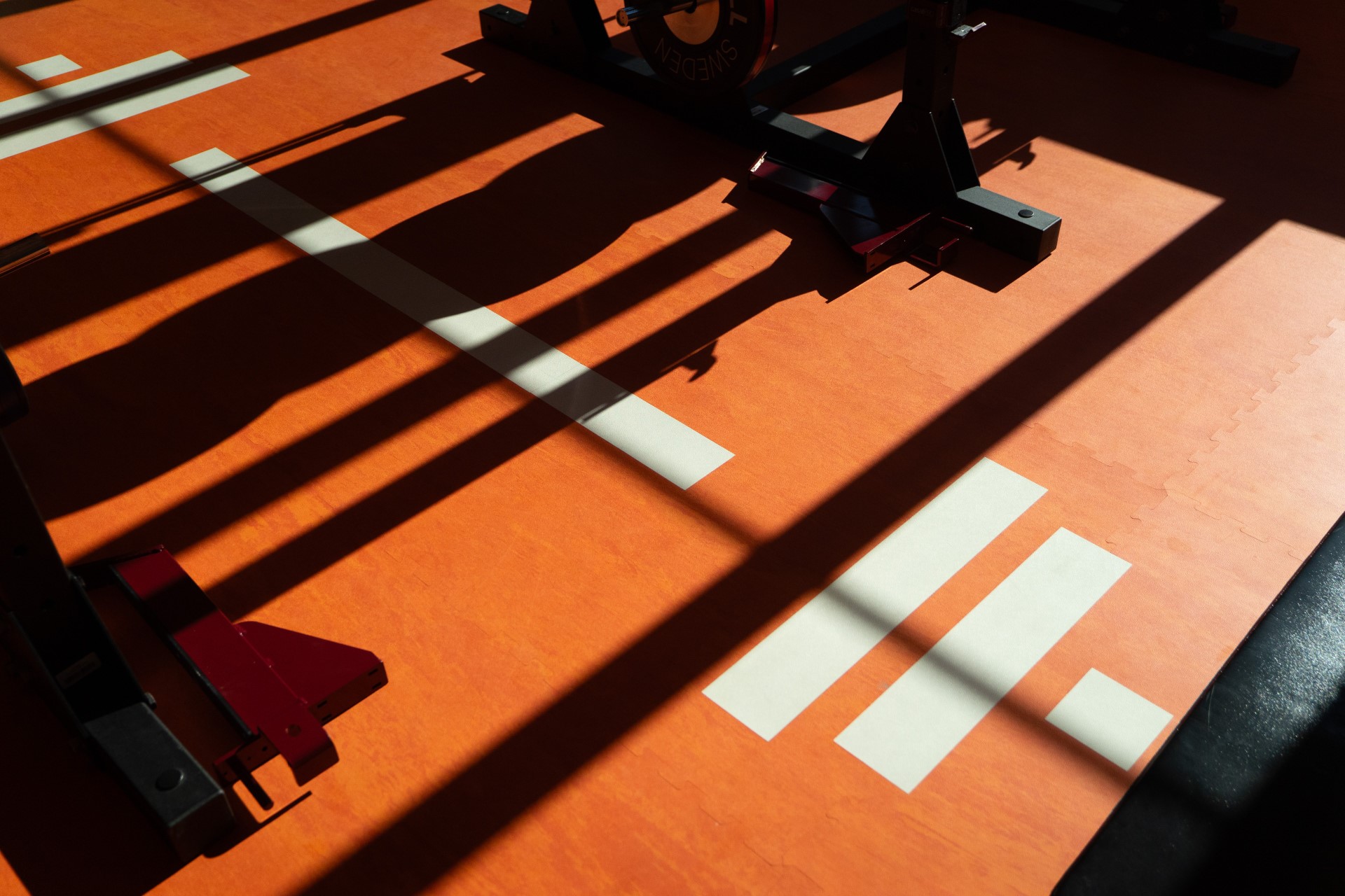 Sunlight and long shadows cross the red training lane at Mornington Health Club Bromma.