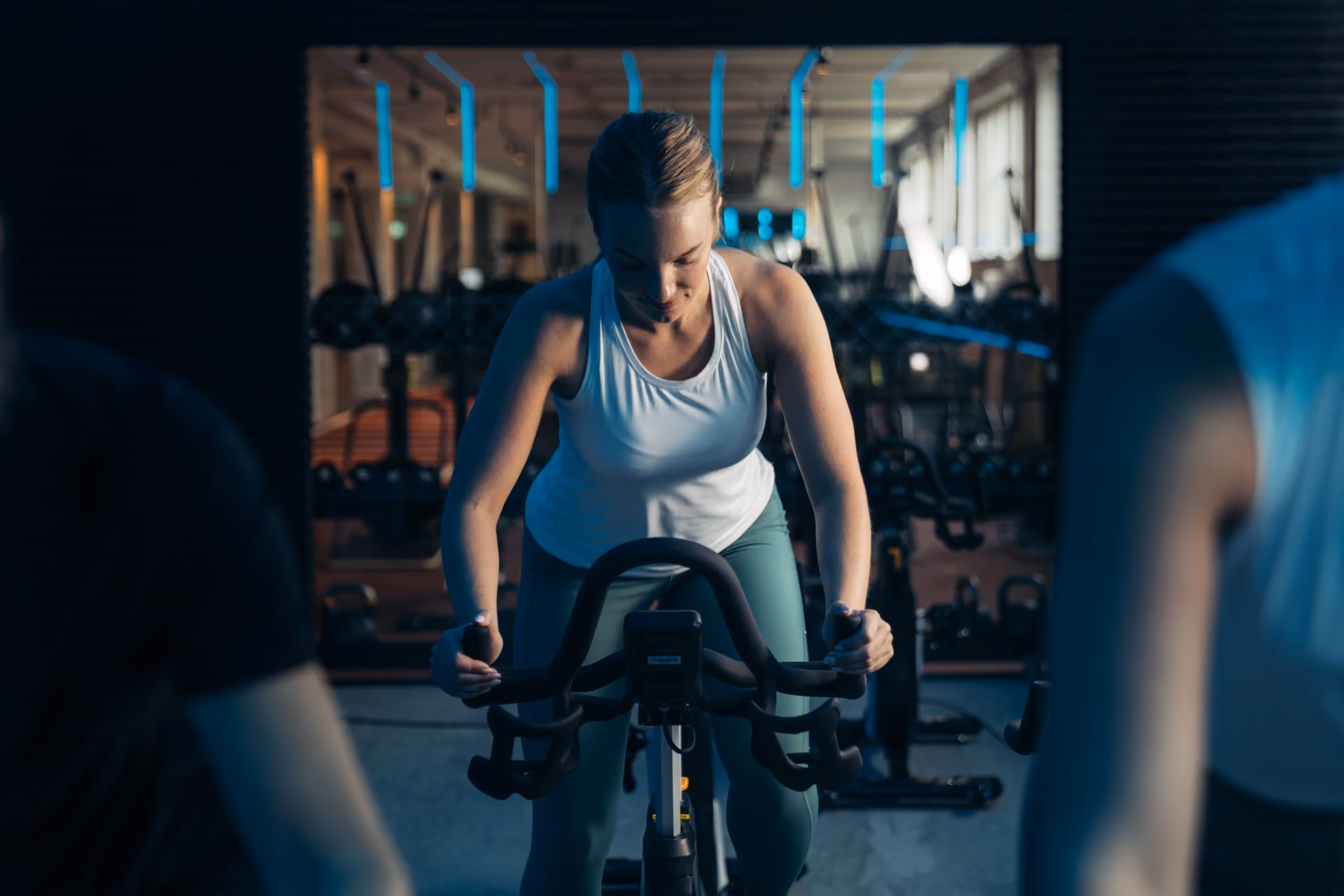 A cyclist trains in a dark studio framed by blue linear lighting.