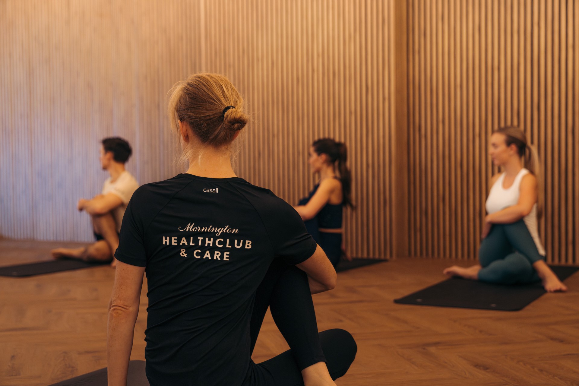 A Mornington instructor leads a seated group session in the warm timber studio.