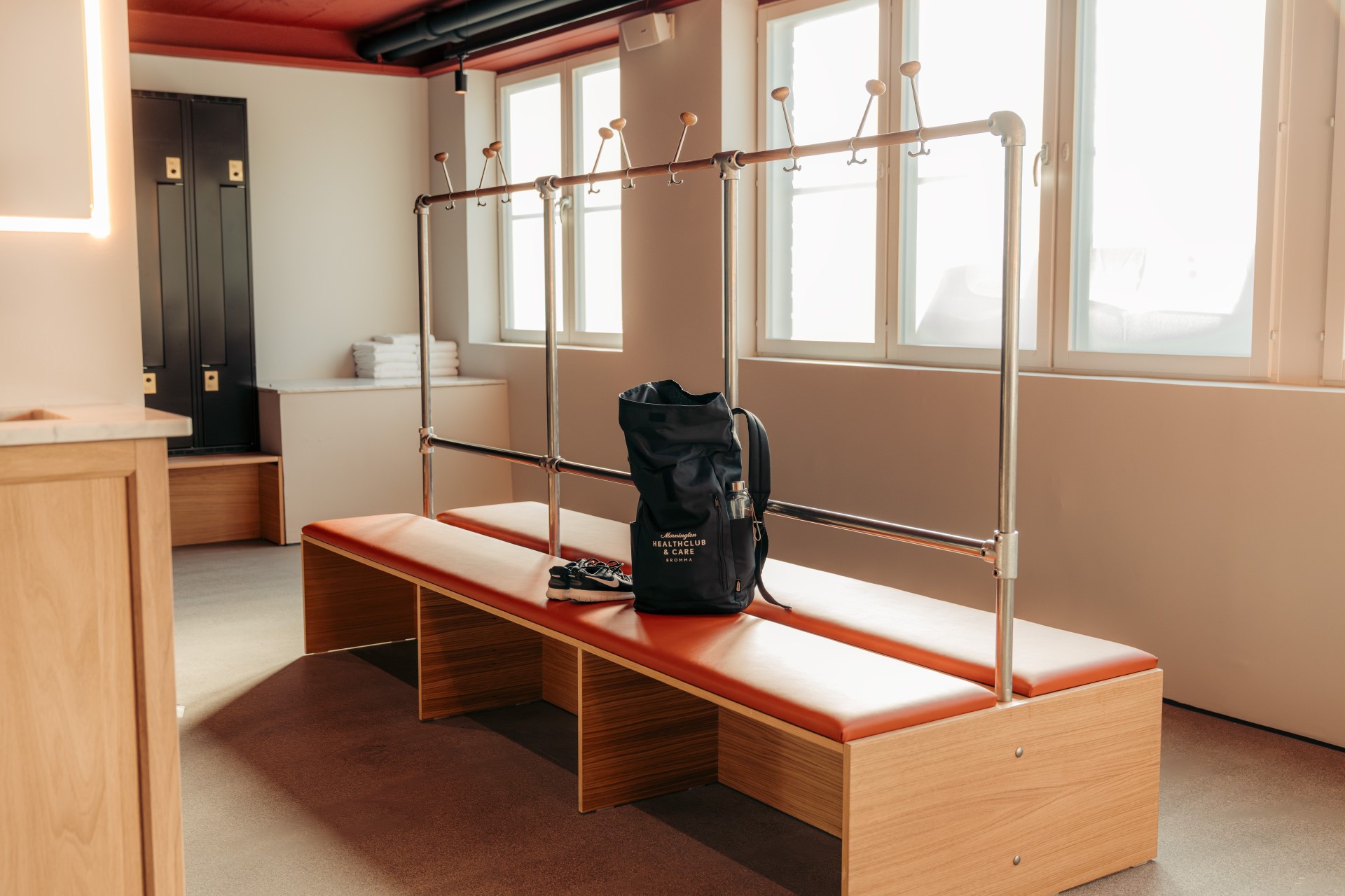 Daylit changing area with timber benches, red upholstery and a Mornington bag.