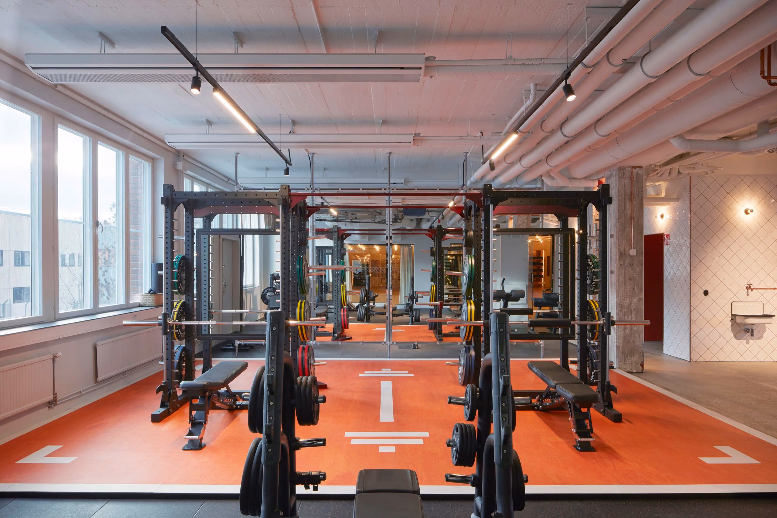 Strength-training equipment arranged within a red exercise zone marked with white directional arrows.