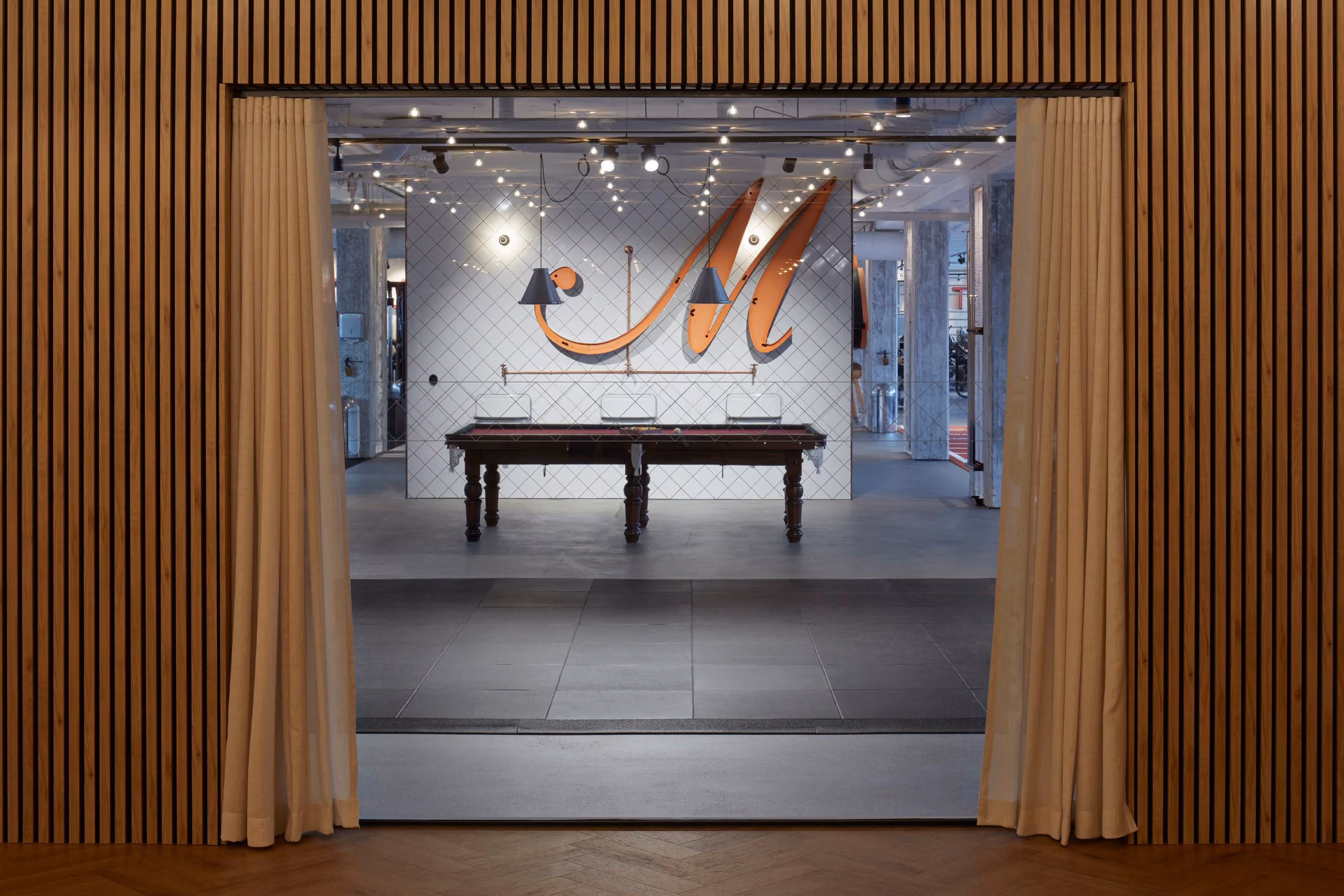 View from the timber studio through a curtained doorway towards the illuminated Mornington M.