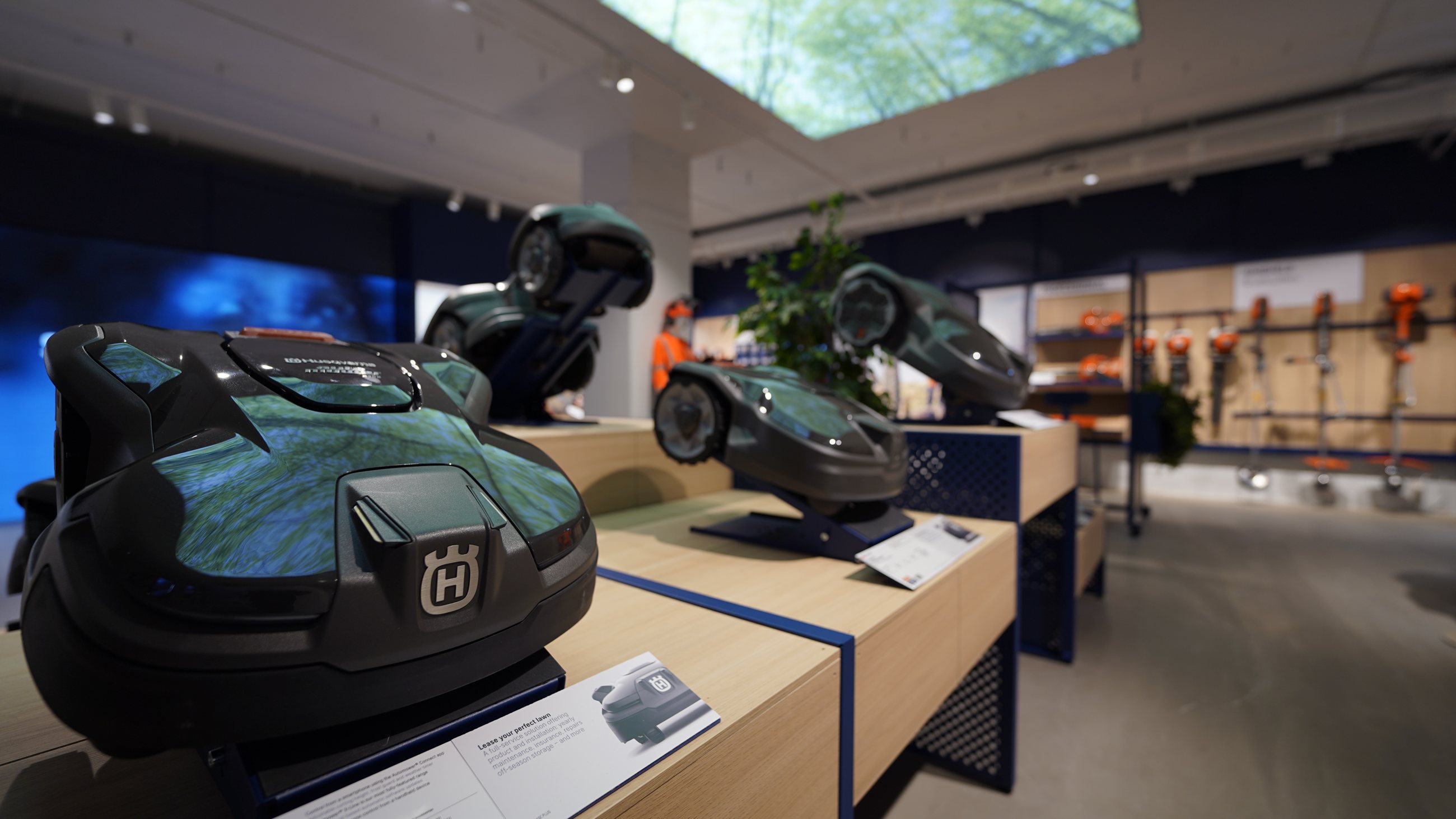 Robotic mowers presented on light wood display tables in the Husqvarna pilot store