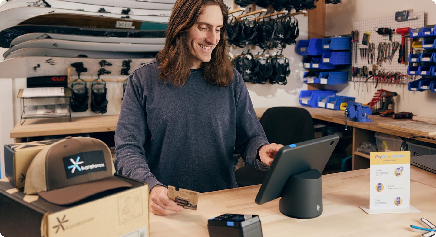 Vendeur, à la caisse d'une quincaillerie, entrant des informations sur le paiement dans un terminal PayPal Terminal