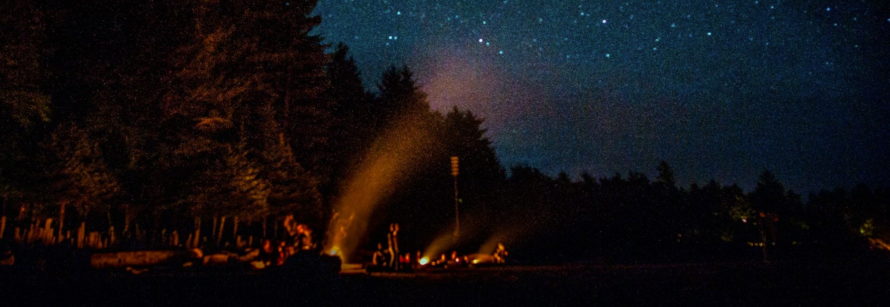 people having bonfire under blue sky filled with stars at night time