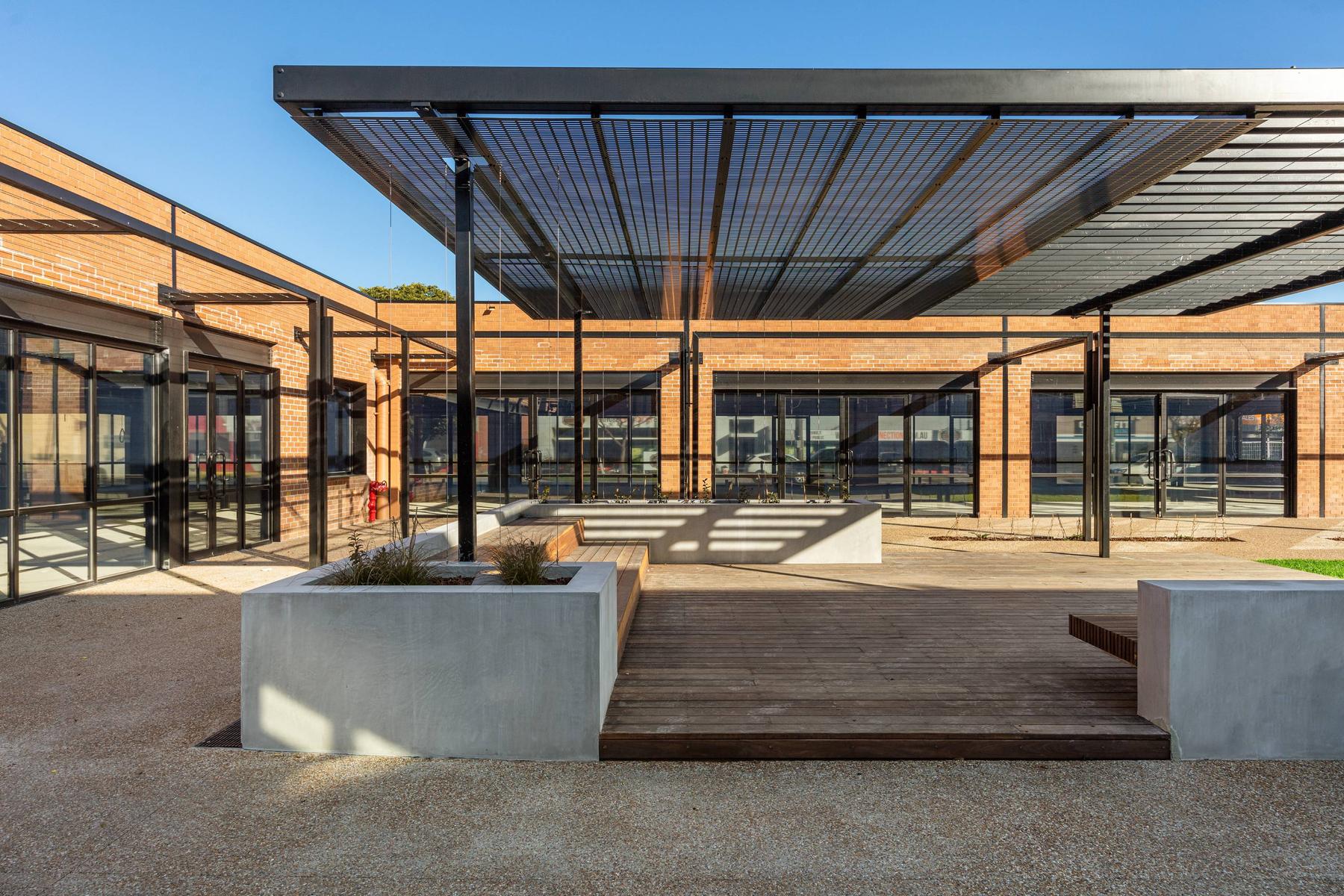 A landscaped courtyard at Morris Moor with a steel canopy and restored brick buildings