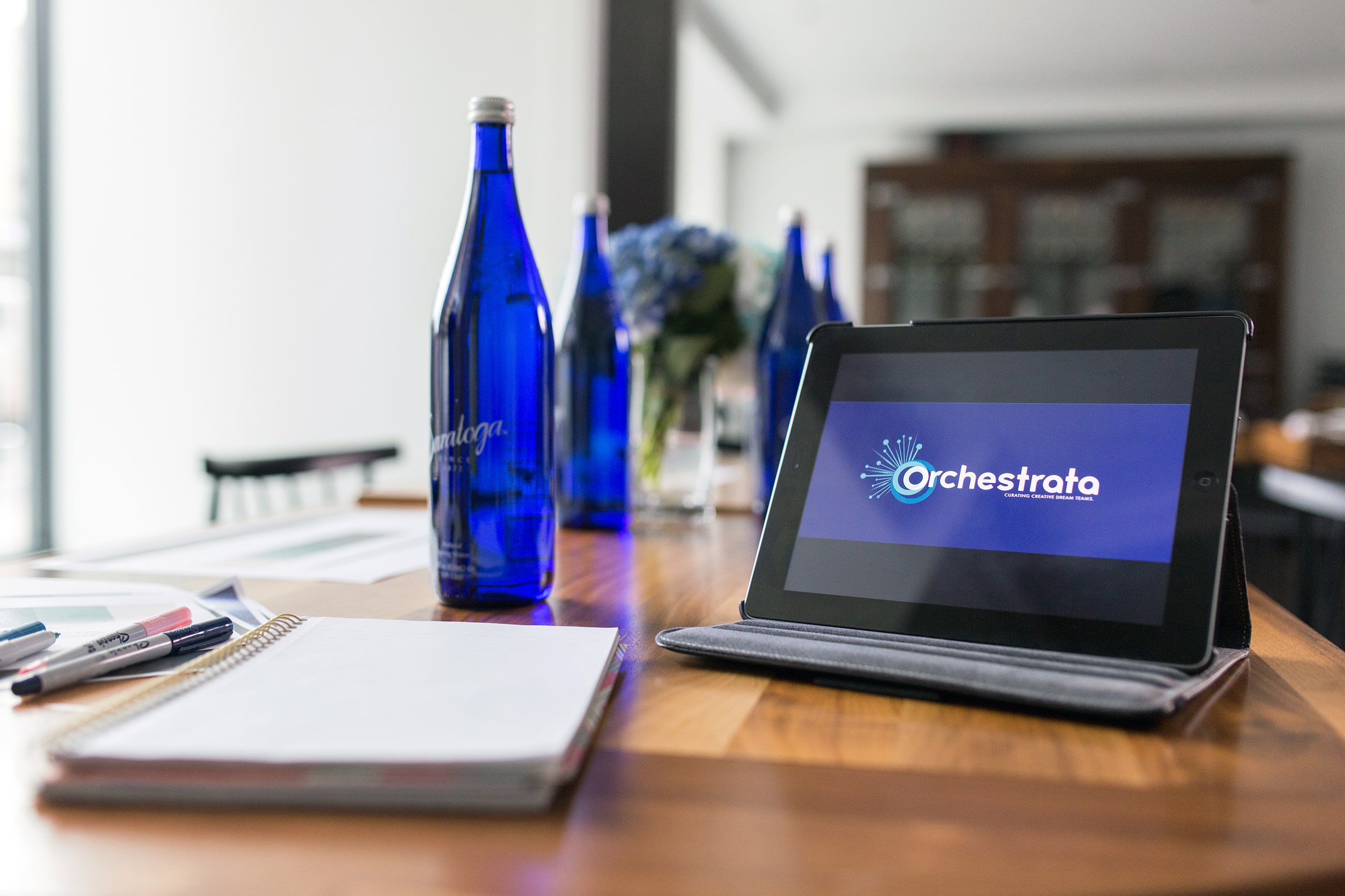 A tablet sitting on a table with a new brand identity on it, surrounded by blue water bottles