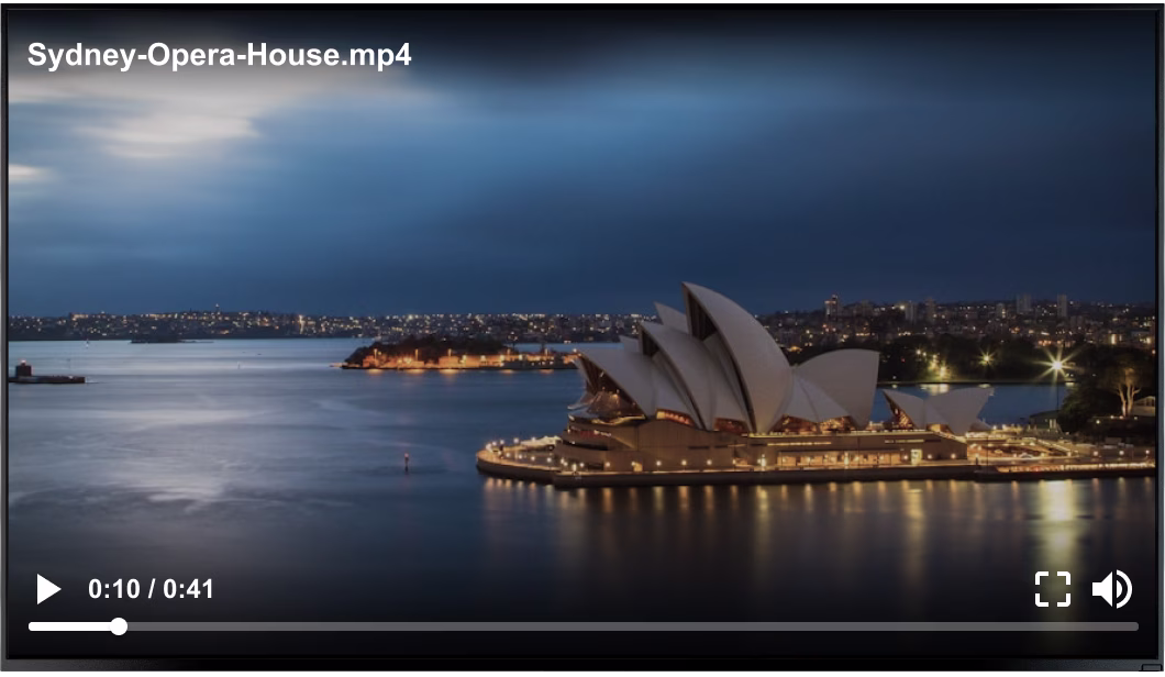 Night view of Sydney Opera House illuminated, surrounded by water and city lights in the background.
