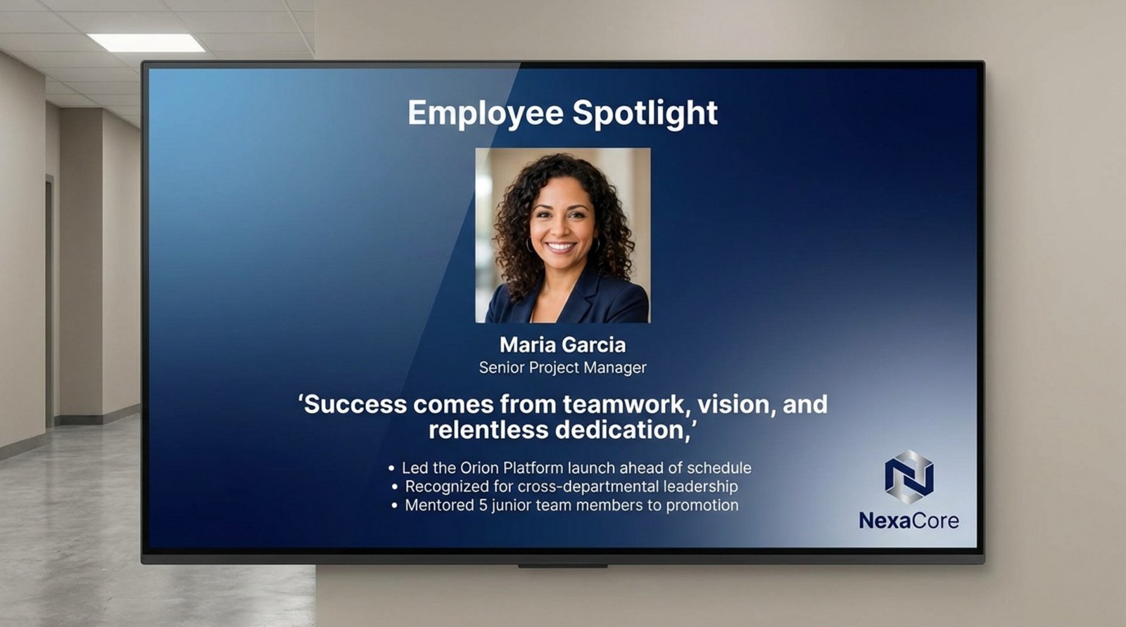 Wall-mounted digital signage displaying an employee spotlight with a smiling headshot and recognition message.