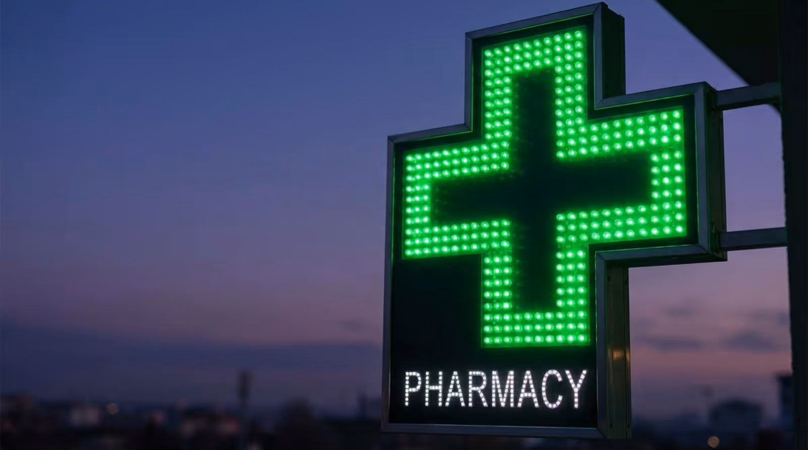 Photorealistic close-up of a bright green LED cross sign for a pharmacy glowing against a dusk sky.