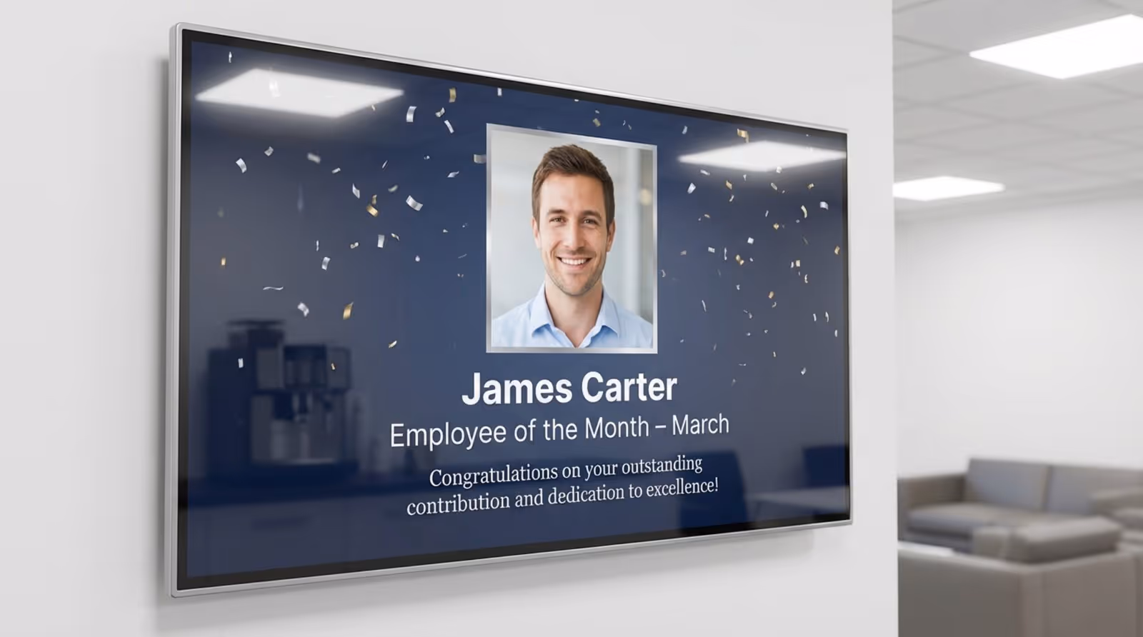 A digital signage screen in a breakroom displaying an employee of the month award with a headshot and congratulatory message.