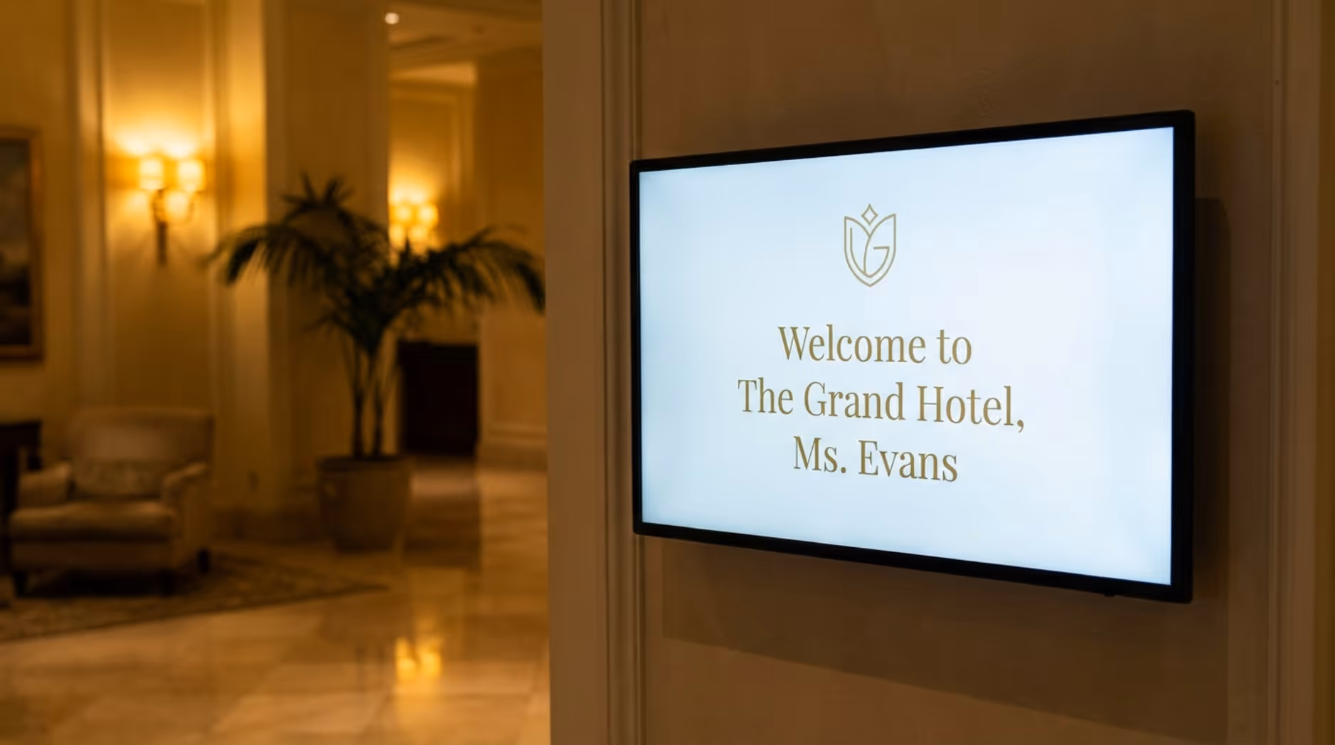 A digital screen at a hotel entrance displays a personalized greeting and the hotel's logo, highlighting premium and personalized service in a luxurious setting.