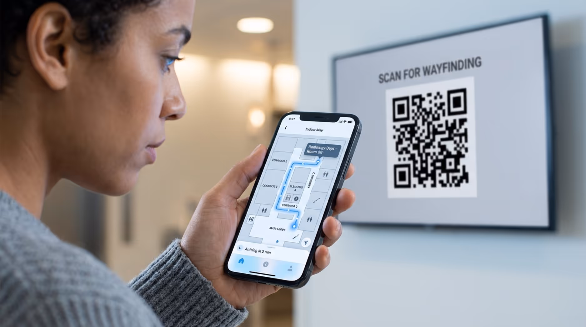A person holds a smartphone displaying a hospital map with a glowing route, linking digital directions to physical signage.