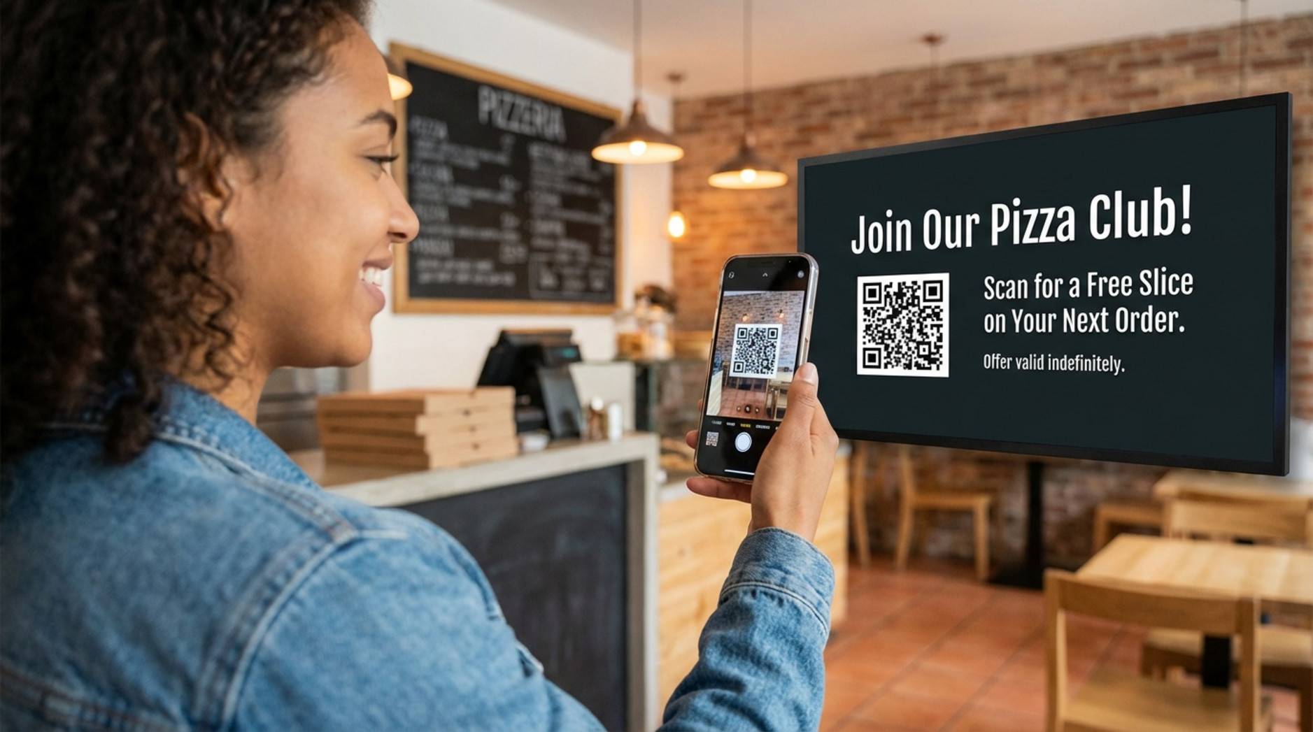 A young adult customer scans a QR code on digital signage at a pizzeria, promoting a loyalty program with a happy expression.