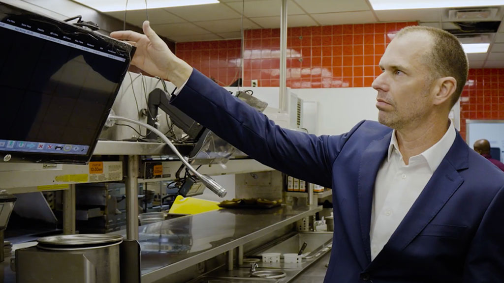 Person in Red Lobster kitchen pointing to digital monitor