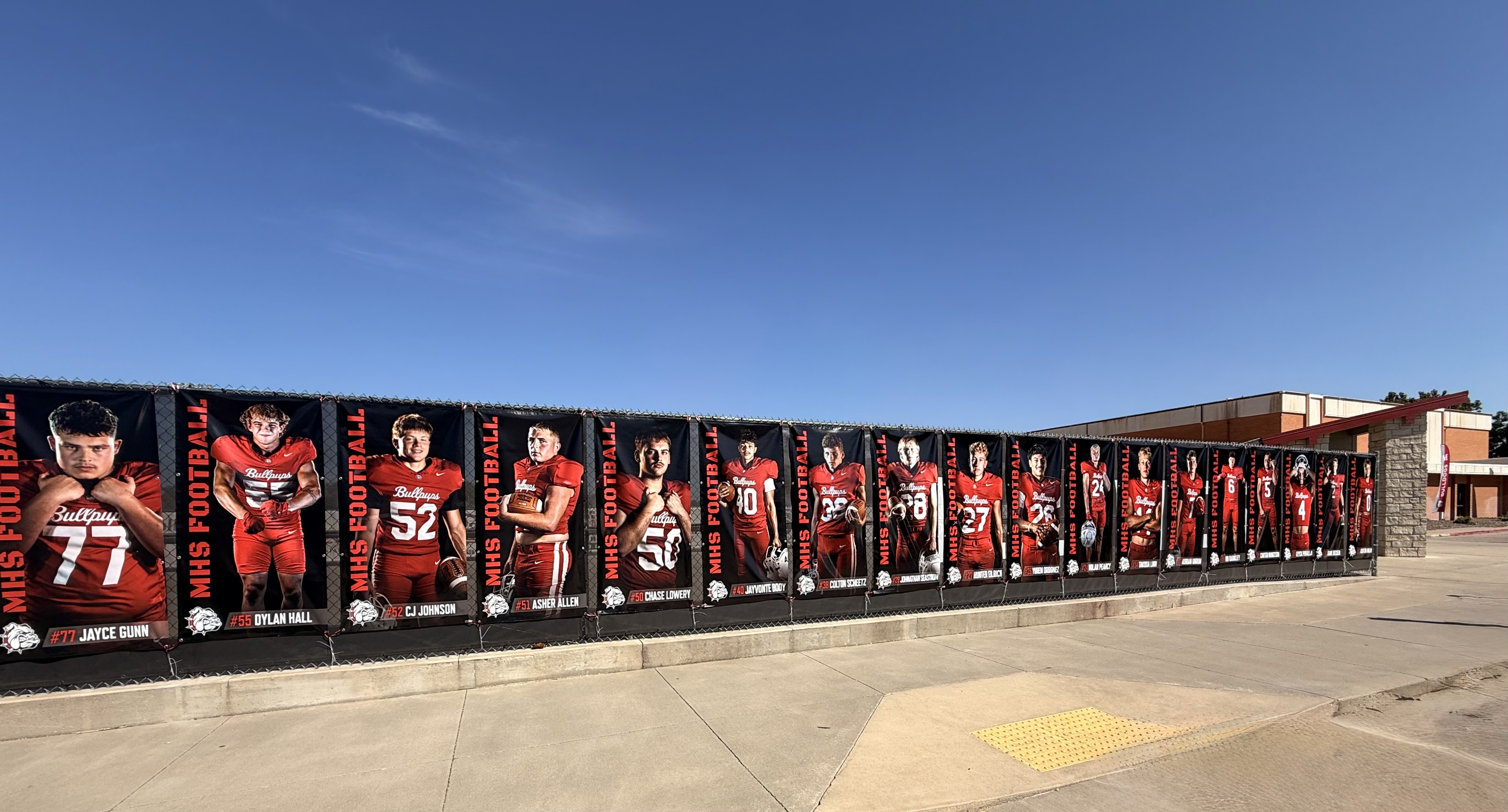 McPherson High School football player vinyl banners displayed along a fence for the Booster Club.