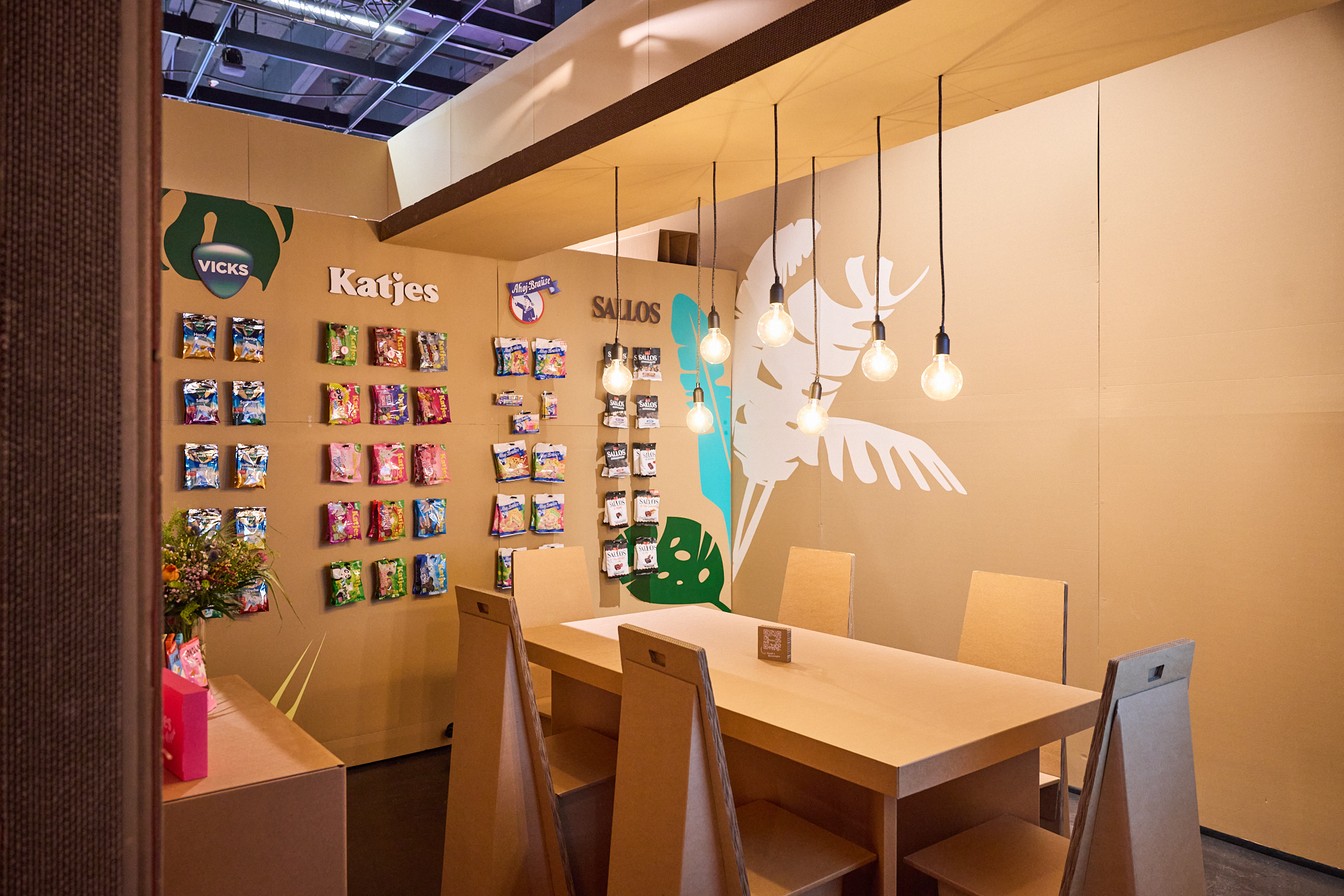 Messefotografie: Innenraum des Katjes Messestands mit Pappmöbeln und bunten Süßigkeiten-Installationen.
