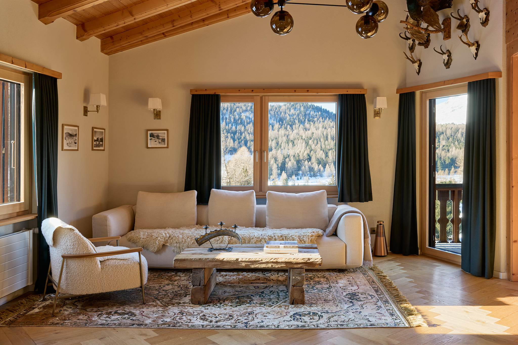 Rustikales Wohnzimmer mit weitem Alpenblick, gemütliche Atmosphäre in zeitgenössischer Architekturfotografie.