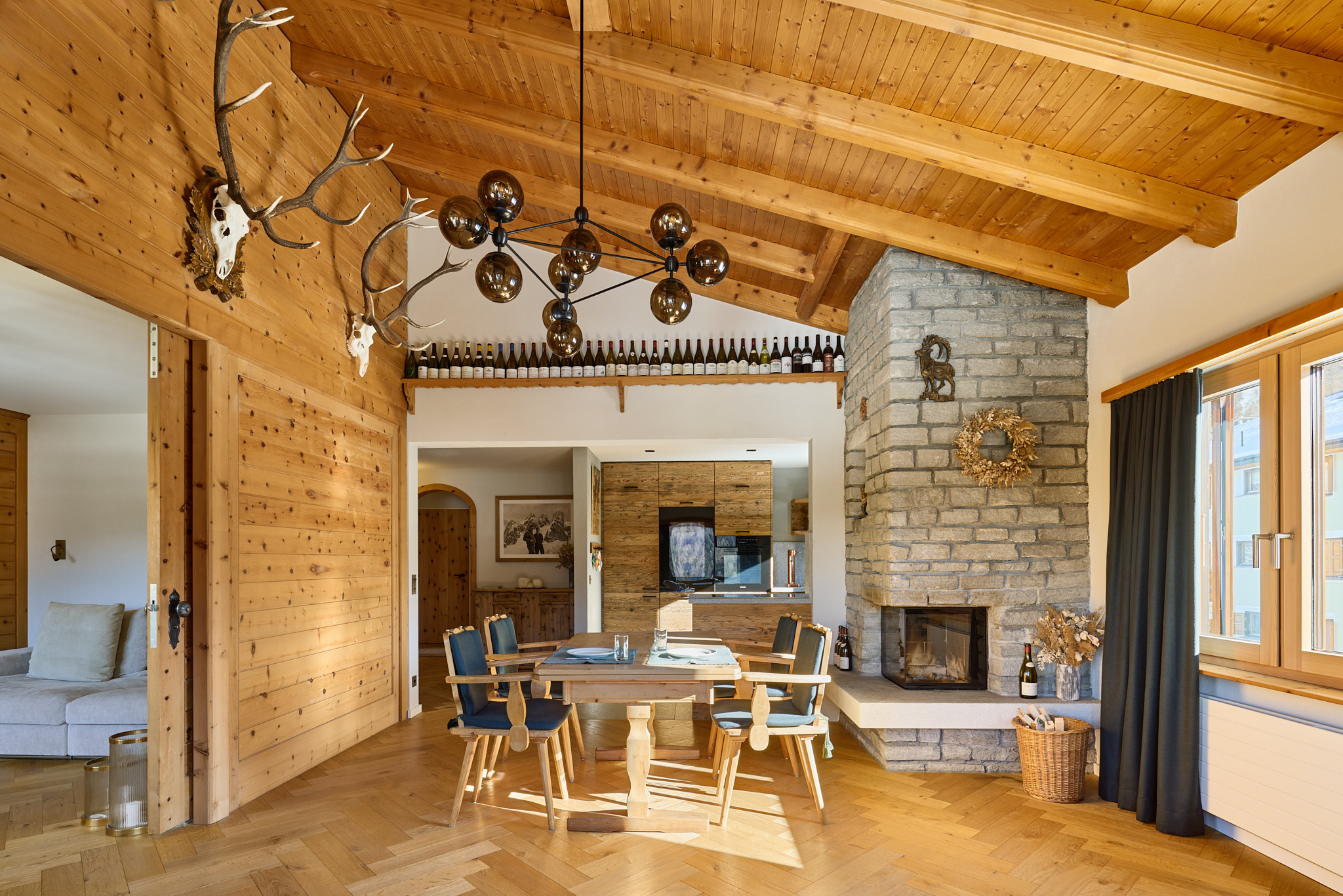 Essbereich mit Kamin und Alpenpanorama, Architekturfotografie mit alpinem Flair und stimmungsvoller Wärme.