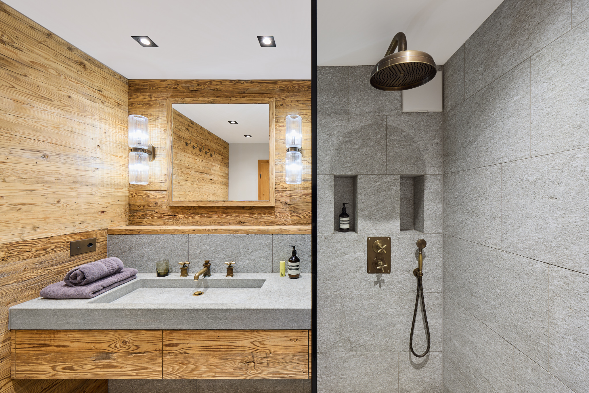 Badezimmer mit Regendusche und Naturmaterialien, alpine Architekturfotografie mit klarer Formensprache.