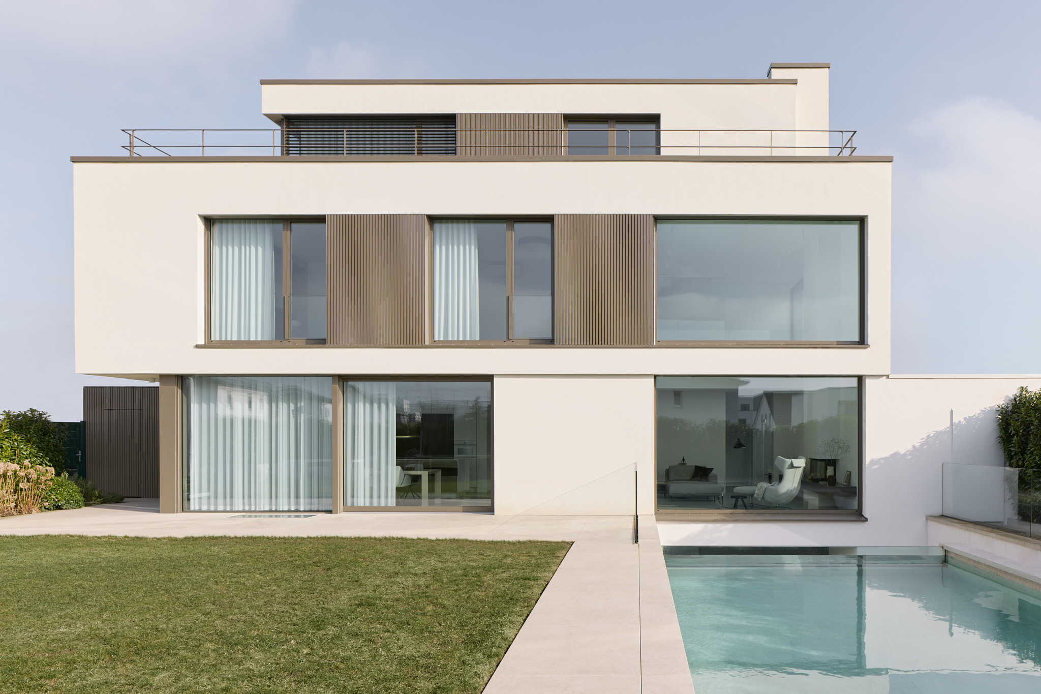 Gartenseite des Hauses mit Fensterfronten und Pool, moderne Architekturfotografie.