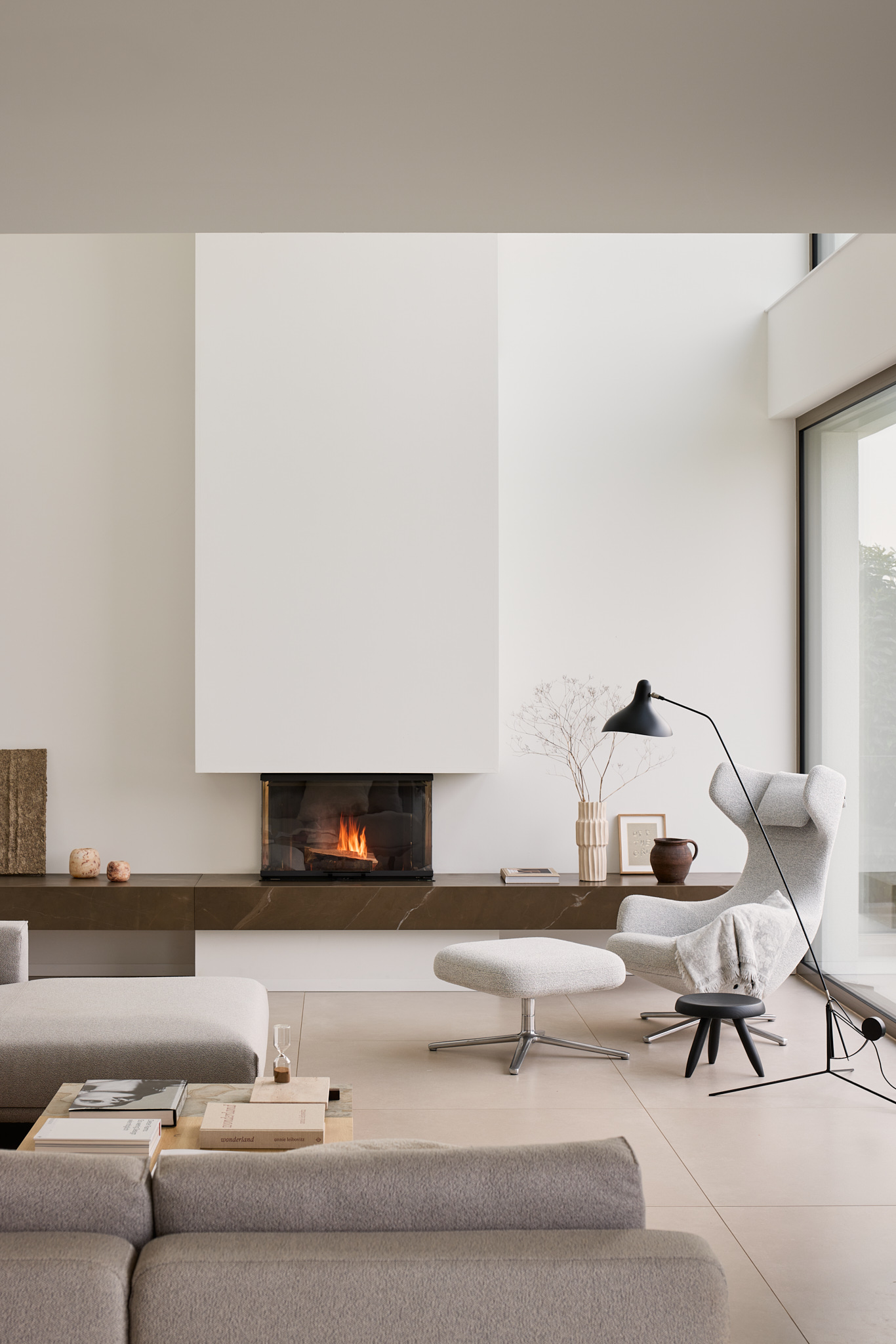 Wohnzimmer mit Kaminfeuer, warme Architekturaufnahme im minimalistischen Wohnhaus Haus K.