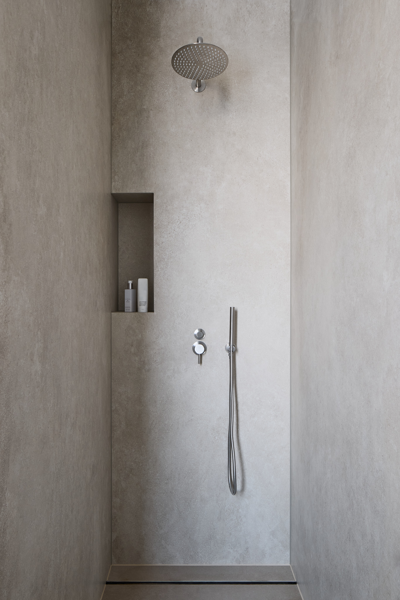 Helle Dusche mit Steinoberflächen, minimalistisches Badezimmerdesign.