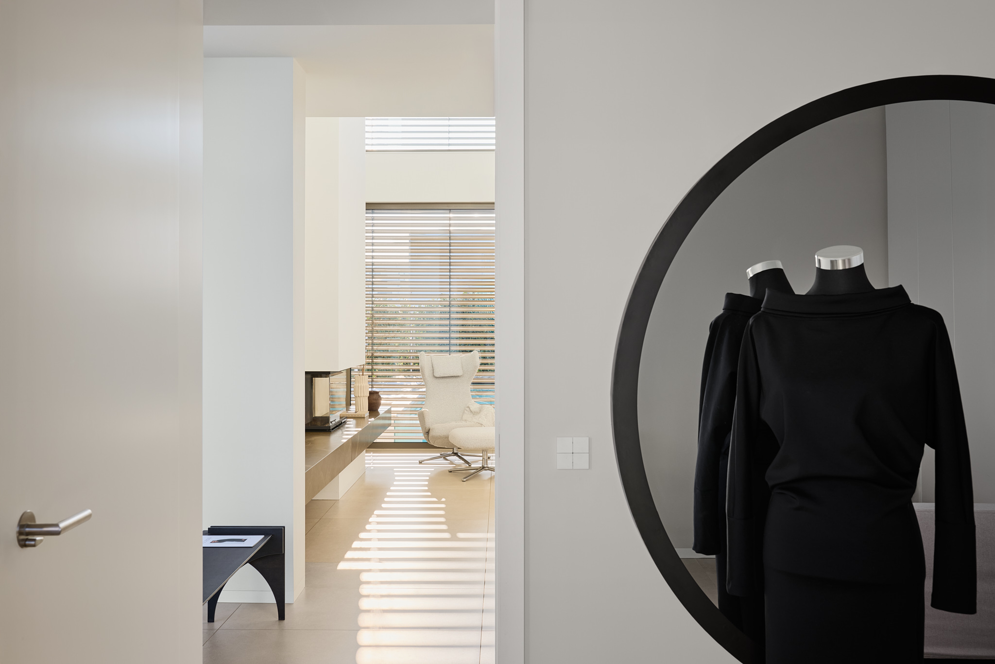 Blick ins Wohnzimmer mit Spiegel, Schneiderpuppe und schwarzem Kleid, dezente Eleganz.