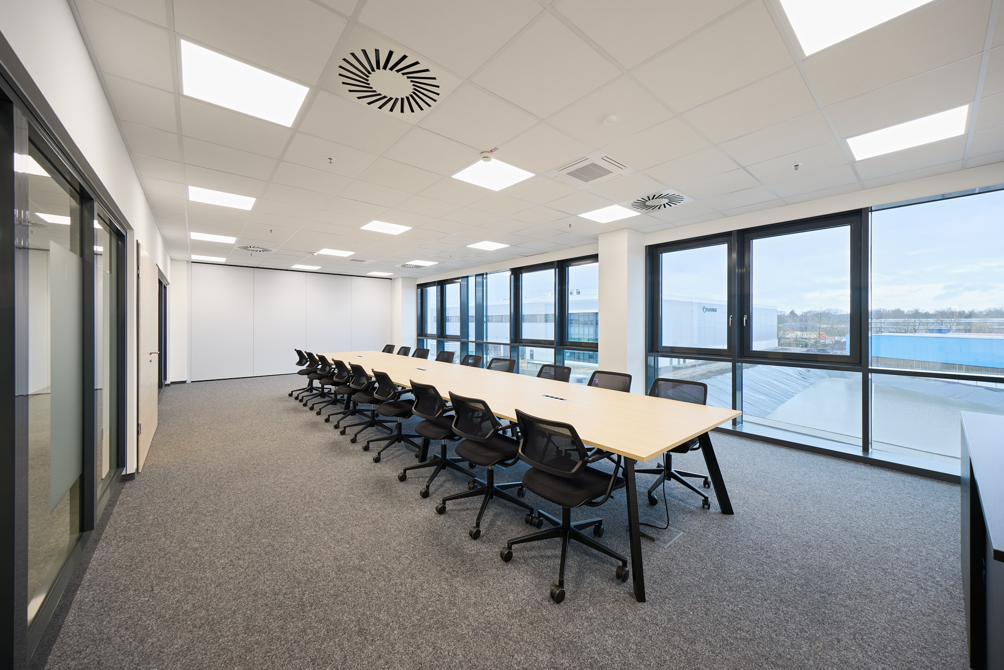 Moderner Meetingraum mit Klimageräten an der Decke, funktionale Innenarchitektur.
