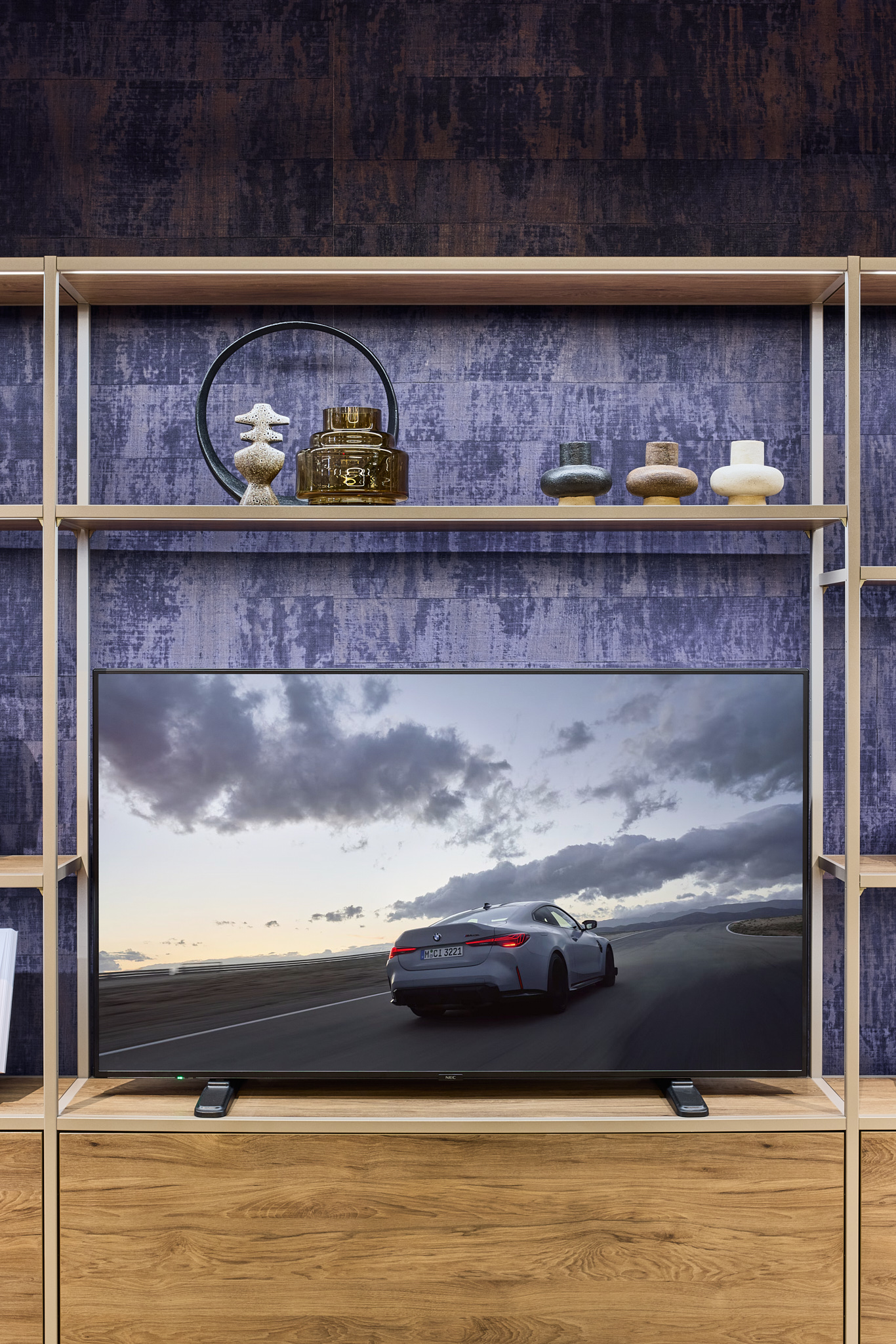 Regal mit Bildschirm und Automobilmotiven, Architekturfotografie zeigt Markenwelt im Raum.