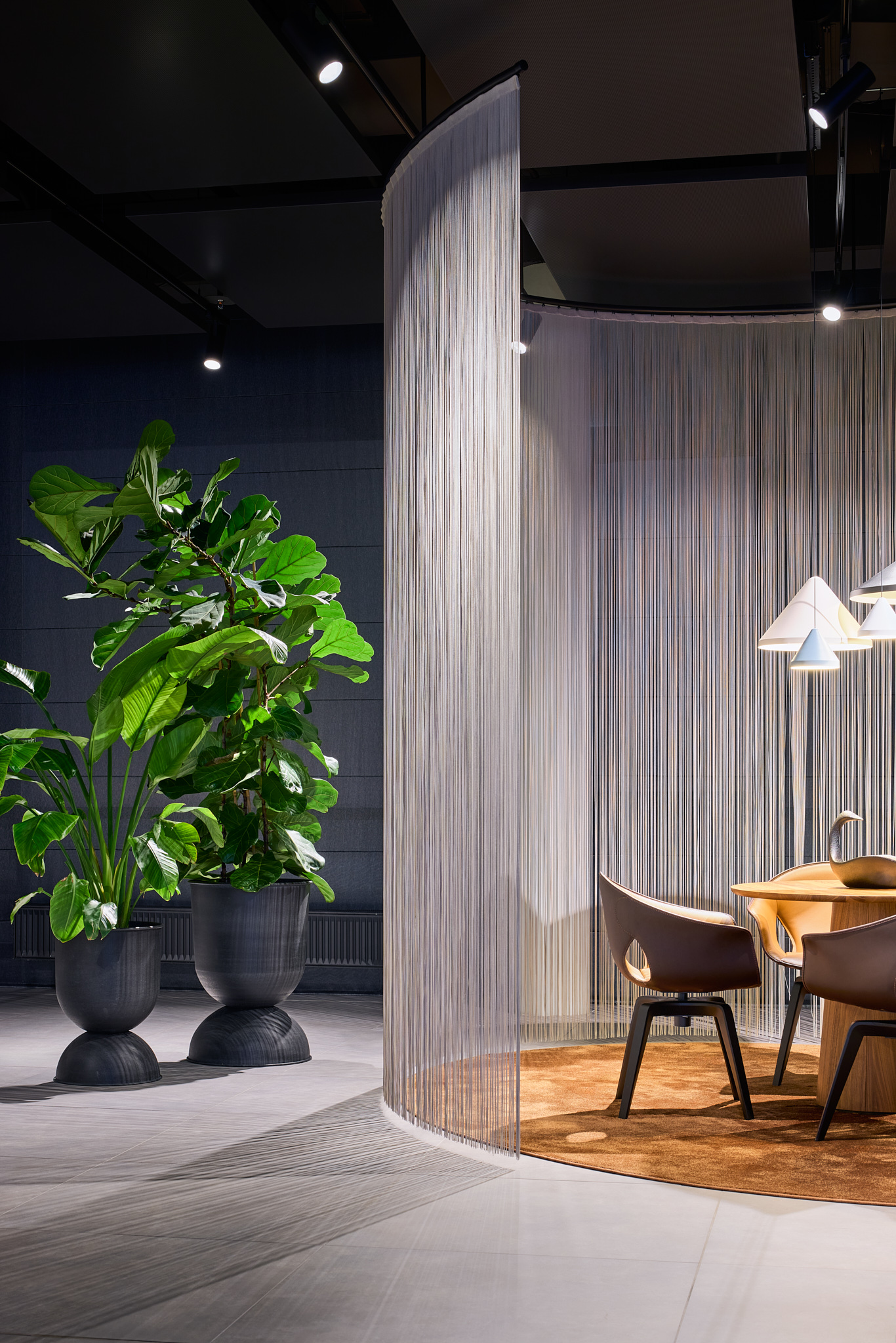 Besprechungsbereich mit Fadenvorhang und Pflanzen, natürliche Akzente im RetailNext Konzept.