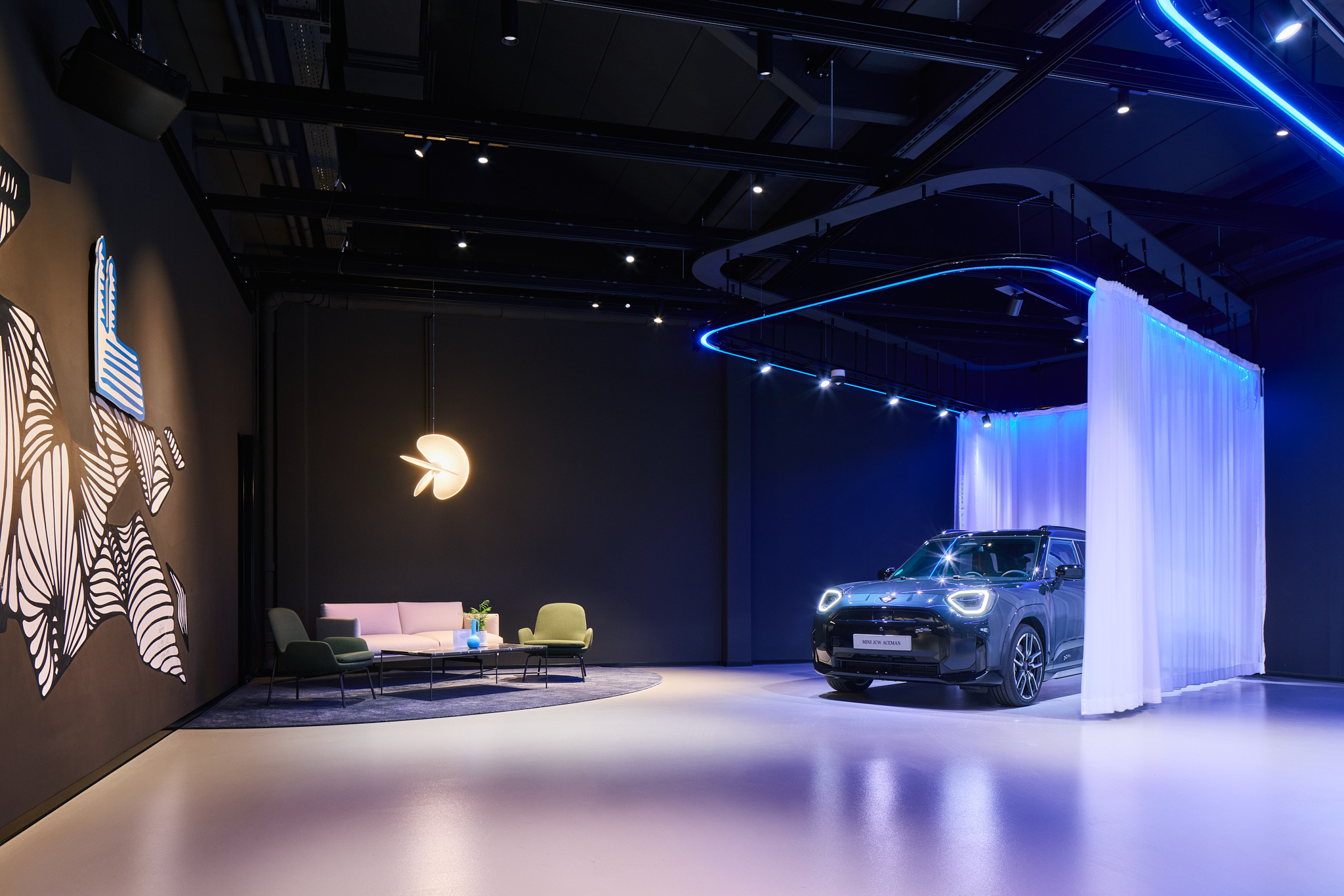 Dunkler Loungebereich mit MINI hinter halbtransparentem Vorhang, stimmungsvolle Architekturfotografie.