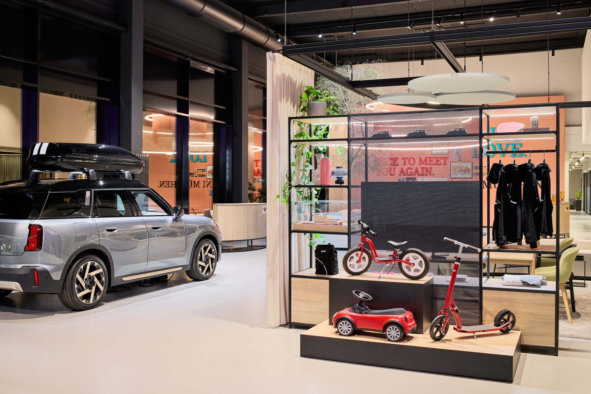 MINI Showroom mit Vorhängen und Regal mit Kaufartikeln, familienfreundliche Markenarchitektur.