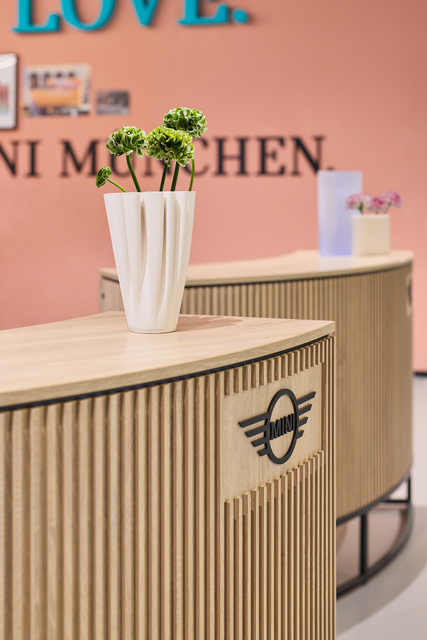Detailaufnahme Dekoration auf Tresen vor rosa Wand, harmonische Markenarchitektur für MINI.