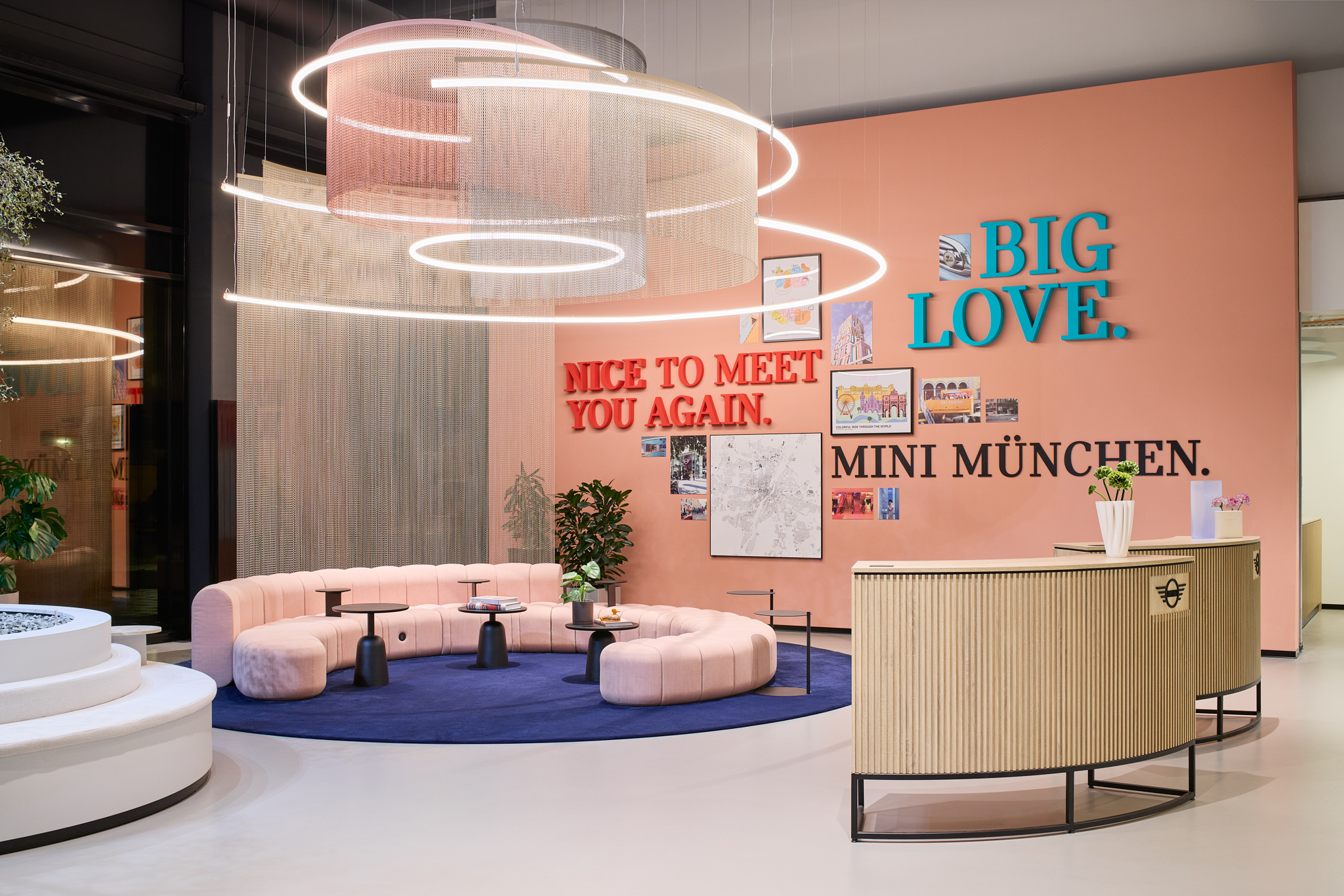 Sitzbereich mit halbrunder Couch, Lichtelementen und Letter Art „MINI München“, lebendige Markenarchitektur.