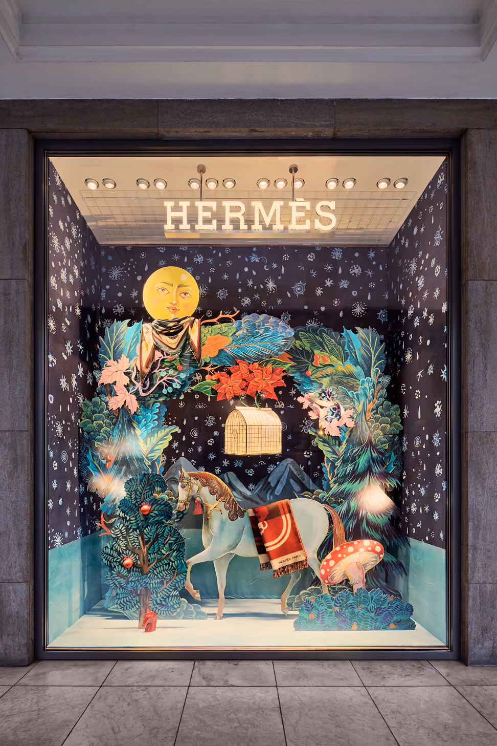 Hermes-Schaufenster mit einem weißen Pferd, großer bunter Kranz, Pilz und leuchtendem Mondgesicht.