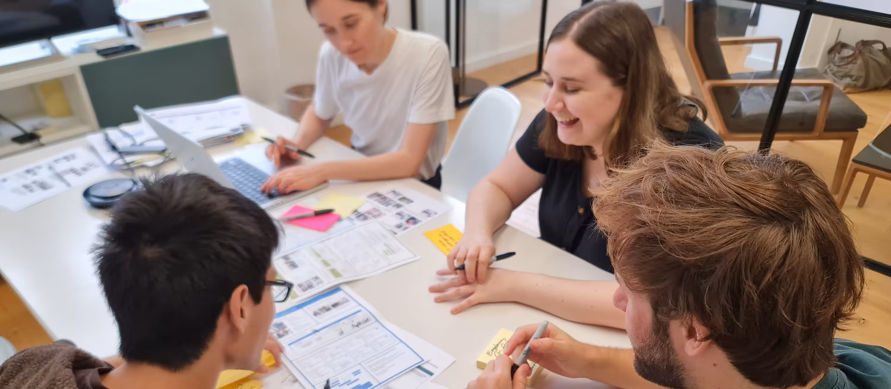 Loomers working together around a table covered in sketches and sticky notes