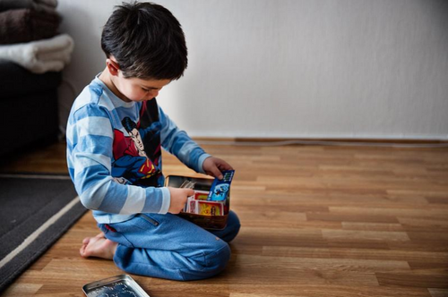 Foto: Lite barn sitter på gulvet og leker for seg selv