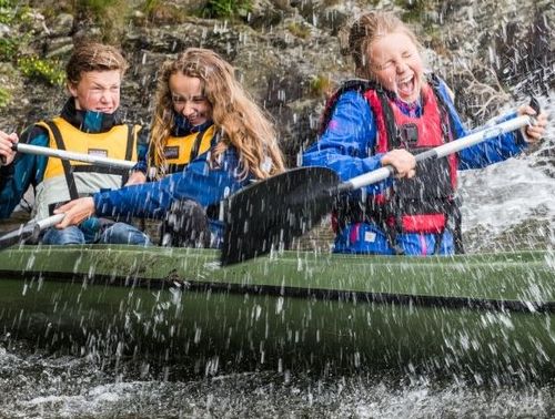 Tre ungdommer sitter i en kano og spruter vann på hverandre. Bilde lånt fra frilager.no.