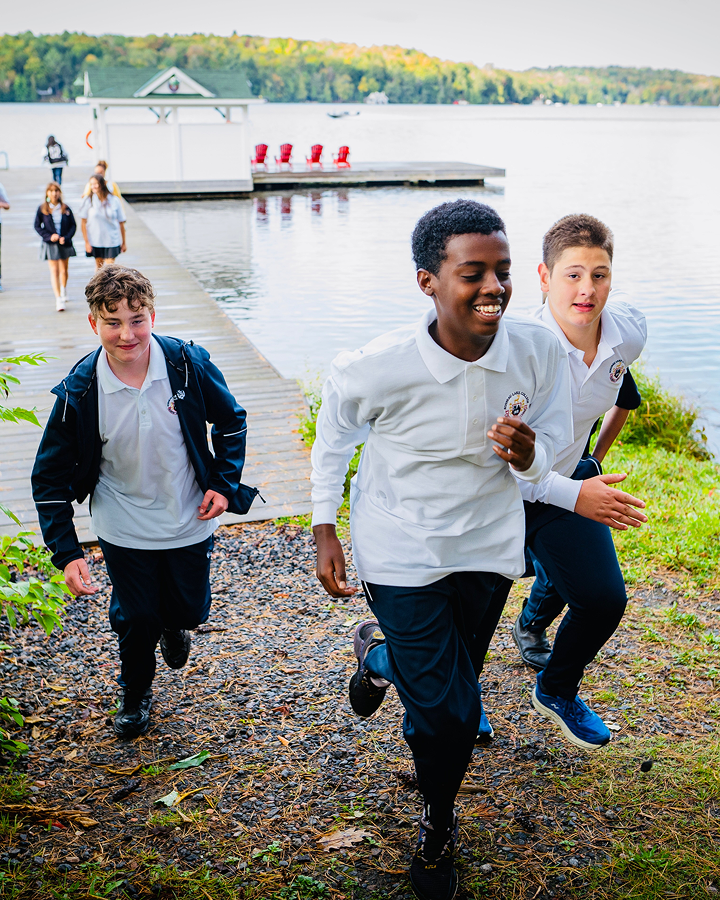 Kids running on the edge of the bank of a river 