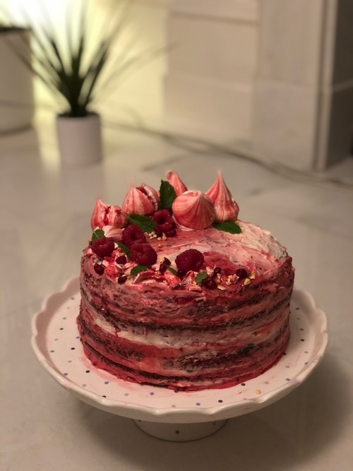 multi layered cake with pink icing topped with meringues